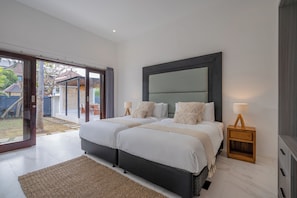 A modern bedroom with a large bed, a nightstand, and a view of the outside. - Luxury 10-bedroom private villa estate located in Seminyak, offering daily breakfast, a full-time private chef, airport transfers, complimentary massages, housekeeping, and a dedicated driver. (Badung)