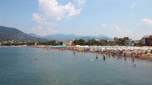 A beach with umbrellas and people swimming. - Charming Apartment Sestri Levante (Sestri Levante)