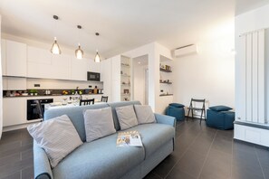 A modern living space with a grey sofa, a dining area, and a kitchen. - Charming Apartment Sestri Levante (Sestri Levante)