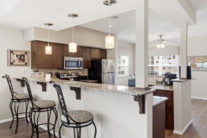 A modern kitchen with dark wooden cabinets, stainless steel appliances, and a marble countertop.