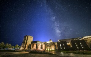 Un edificio histórico con fachada de piedra, una torre central y una entrada bien iluminada.