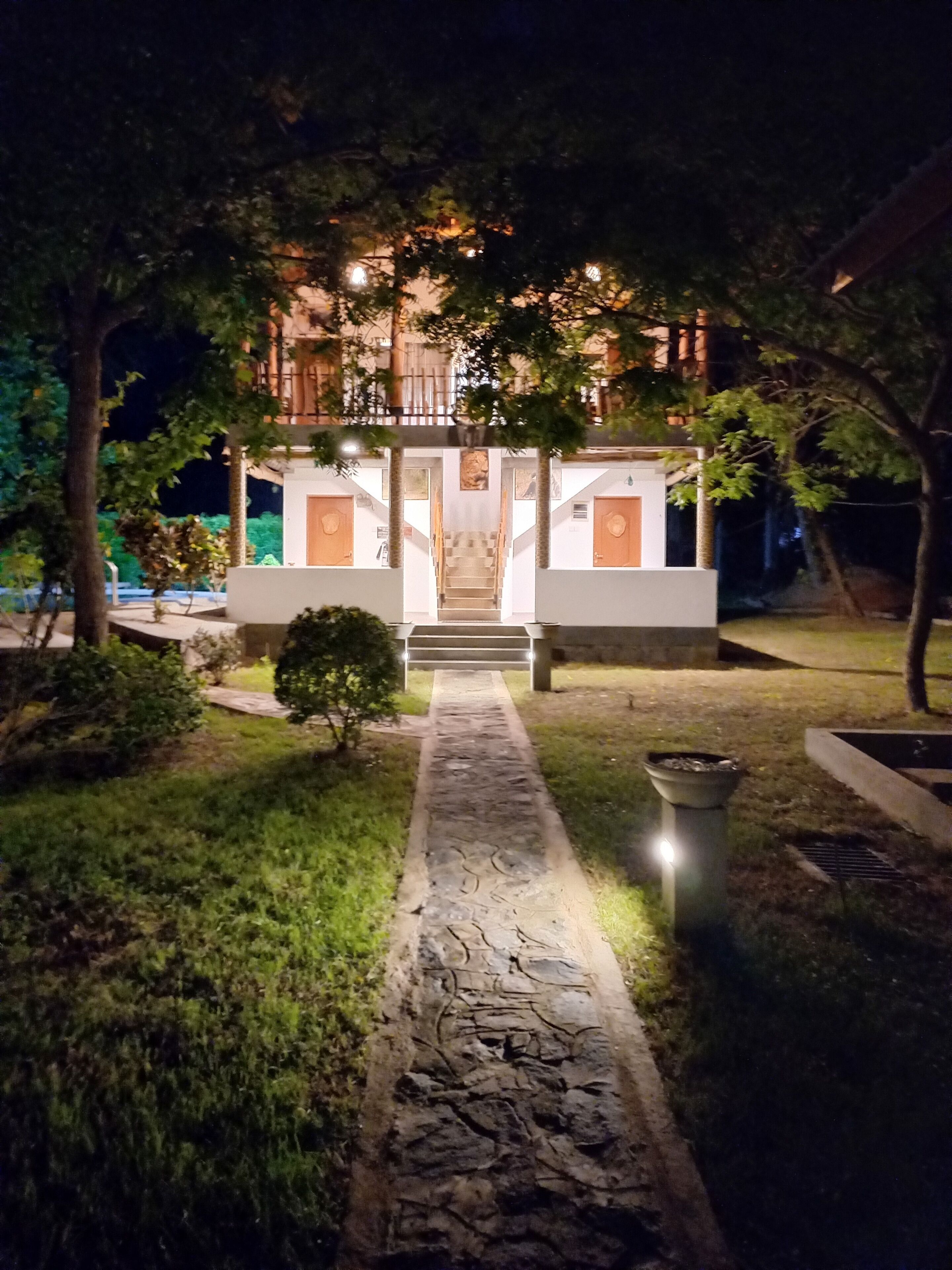 Un edificio moderno con una scalinata centrale, circondato da alberi e un vialetto in pietra che conduce all'ingresso.
