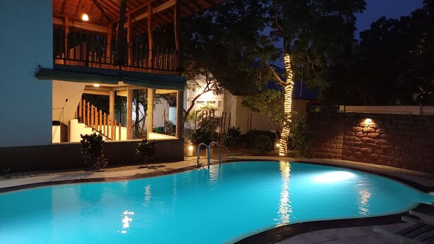 A swimming pool with a wooden deck and a covered area with seating. - yala leopard lodge (Kirinda)