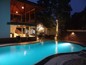 A swimming pool with a wooden deck and a covered area with seating. - yala leopard lodge (Kirinda)