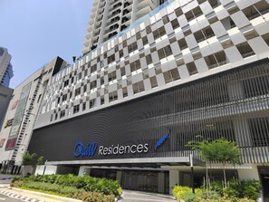 A modern building with a prominent 'Owl Residences' sign, featuring a unique geometric facade and a large entrance area.