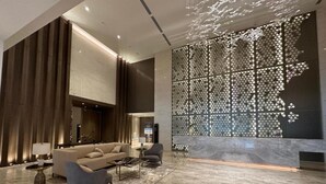 A spacious lobby with a modern sofa set, a coffee table, and a decorative wall with a geometric pattern. - OYO 90952 Quill Residences Kuala Lumpur (Kuala Lumpur)