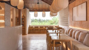 A restaurant with wooden furniture, hanging paper lanterns, and a view of greenery outside. - Dune Seseh (Cemagi)