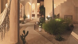A courtyard with a hammock, palm trees, and a staircase leading to an upper level. - Dune Seseh (Cemagi)