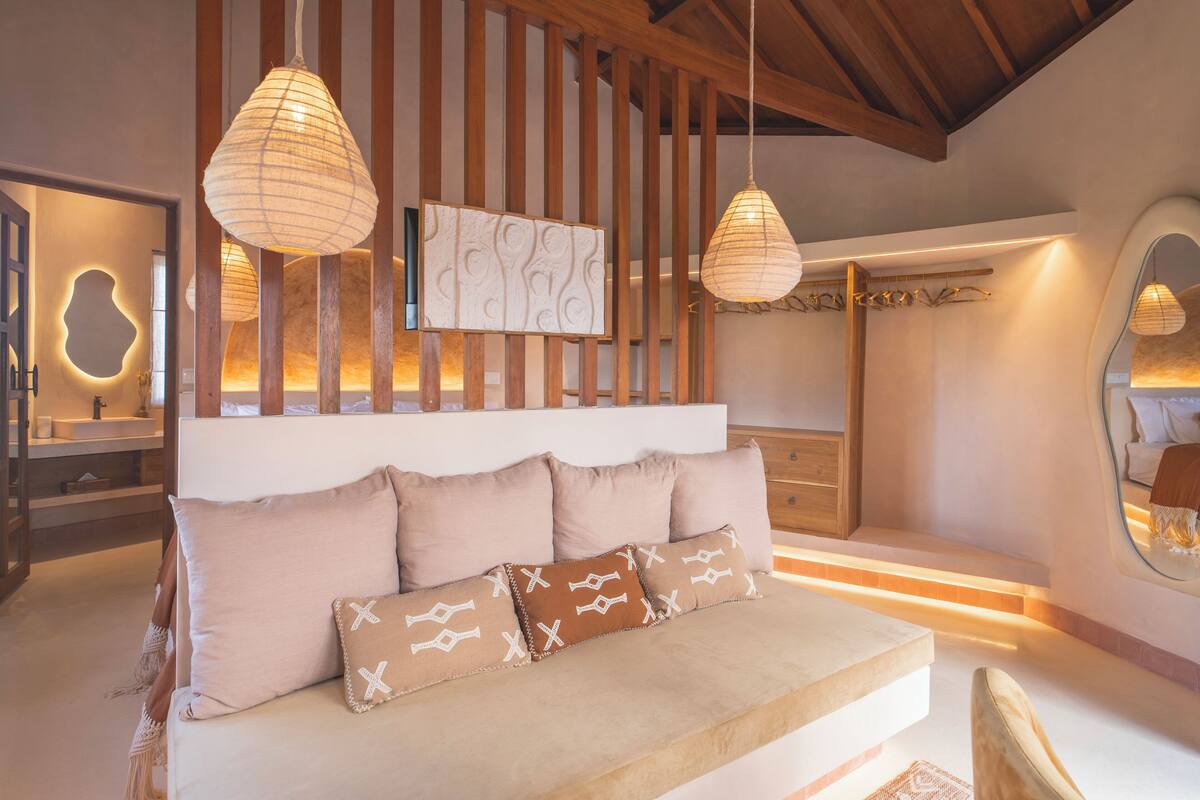 A modern bedroom with a large bed, wooden slats, and pendant lighting.