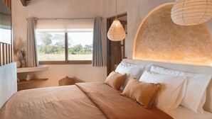 A bedroom with a large bed, a window with curtains, and two hanging paper lamps. - Dune Seseh (Cemagi)