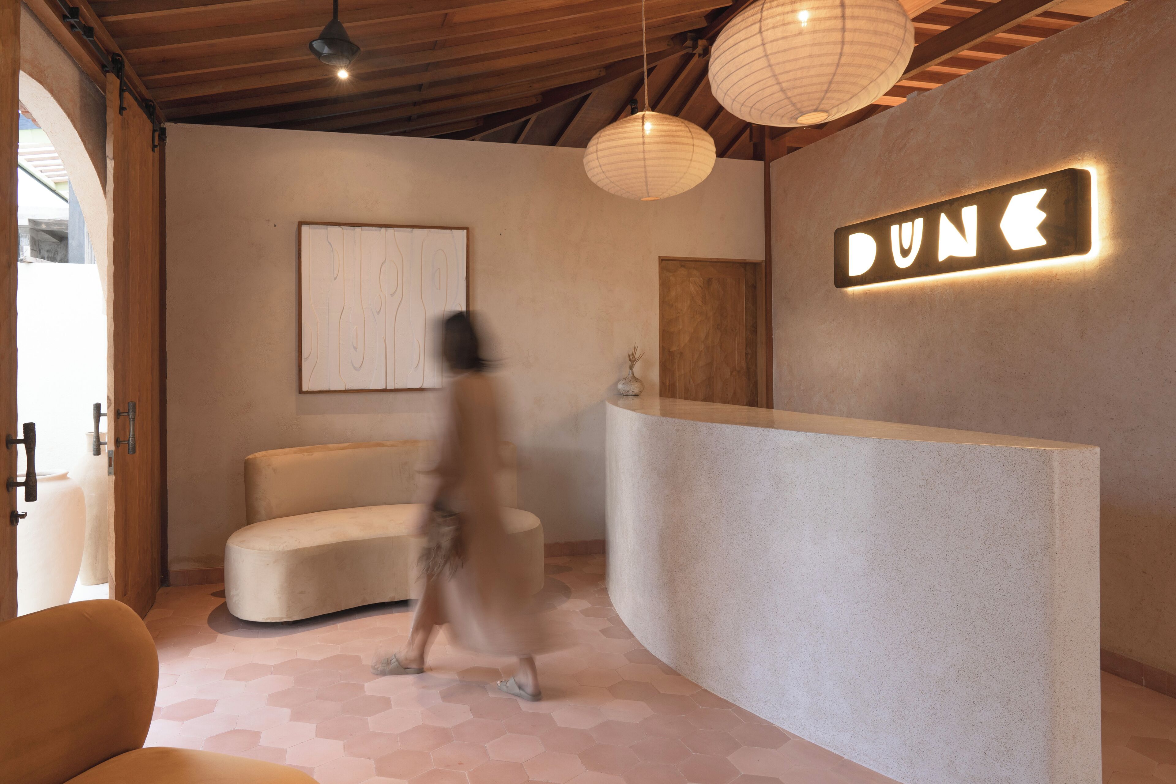 A modern reception area with a curved reception desk, a sign indicating 'DUNE', and a large abstract painting on the wall.