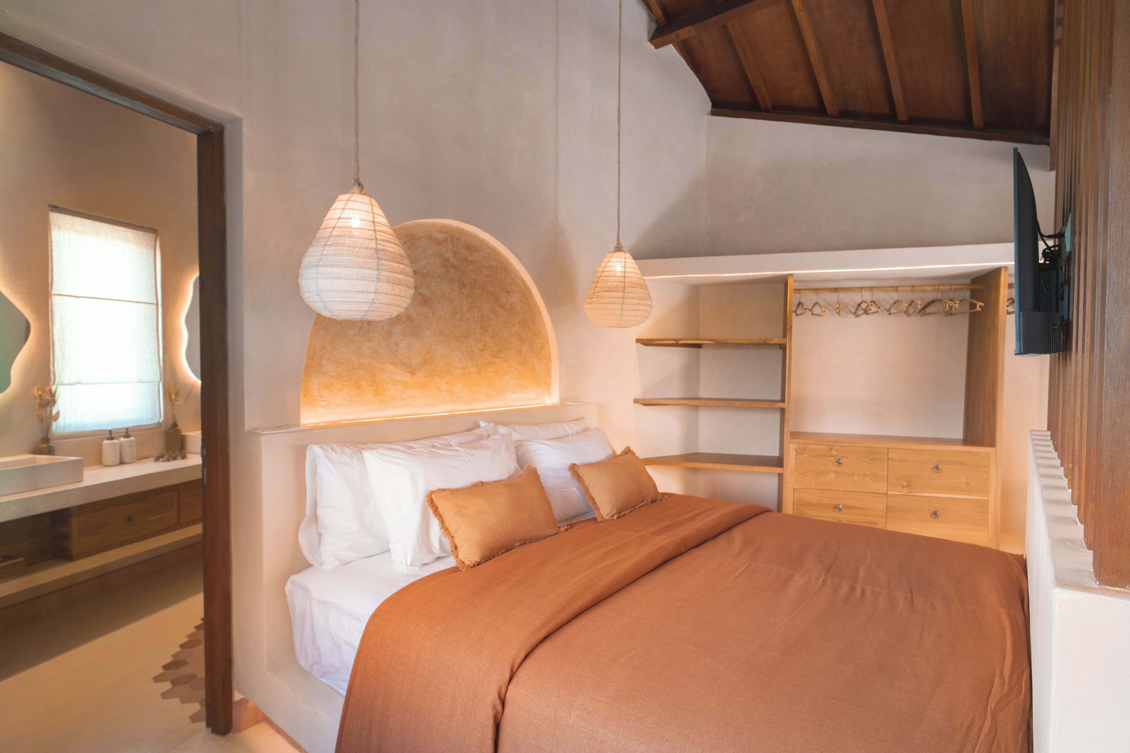 A bedroom with a large bed, a wooden wardrobe, and a built-in shelf unit.