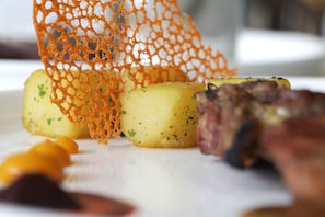 Un plato con alimentos, incluyendo papas y carne, y una red naranja decorativa.
