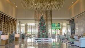 Un vestíbulo amplio con un gran árbol de Navidad, zonas de estar y una recepción.