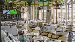 Ein moderner Lounge-Bereich mit Sofas, Korbstühlen und runden Tischen.