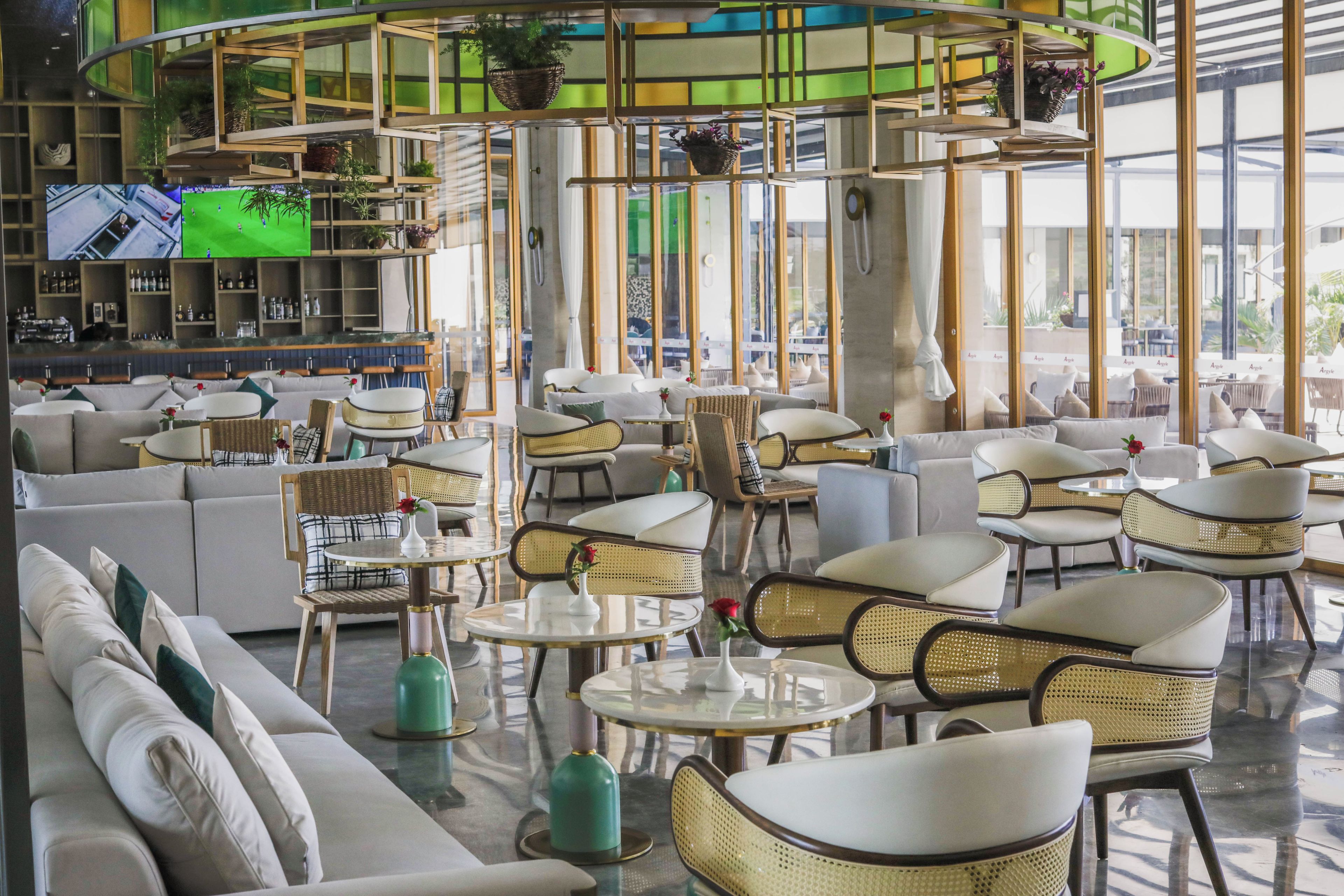A modern lounge area with sofas, wicker chairs, and round tables.