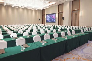 A conference room with rows of tables, each with a green tablecloth, white chairs, and water bottles. - Argyle Grand Hotel (Syokimau)