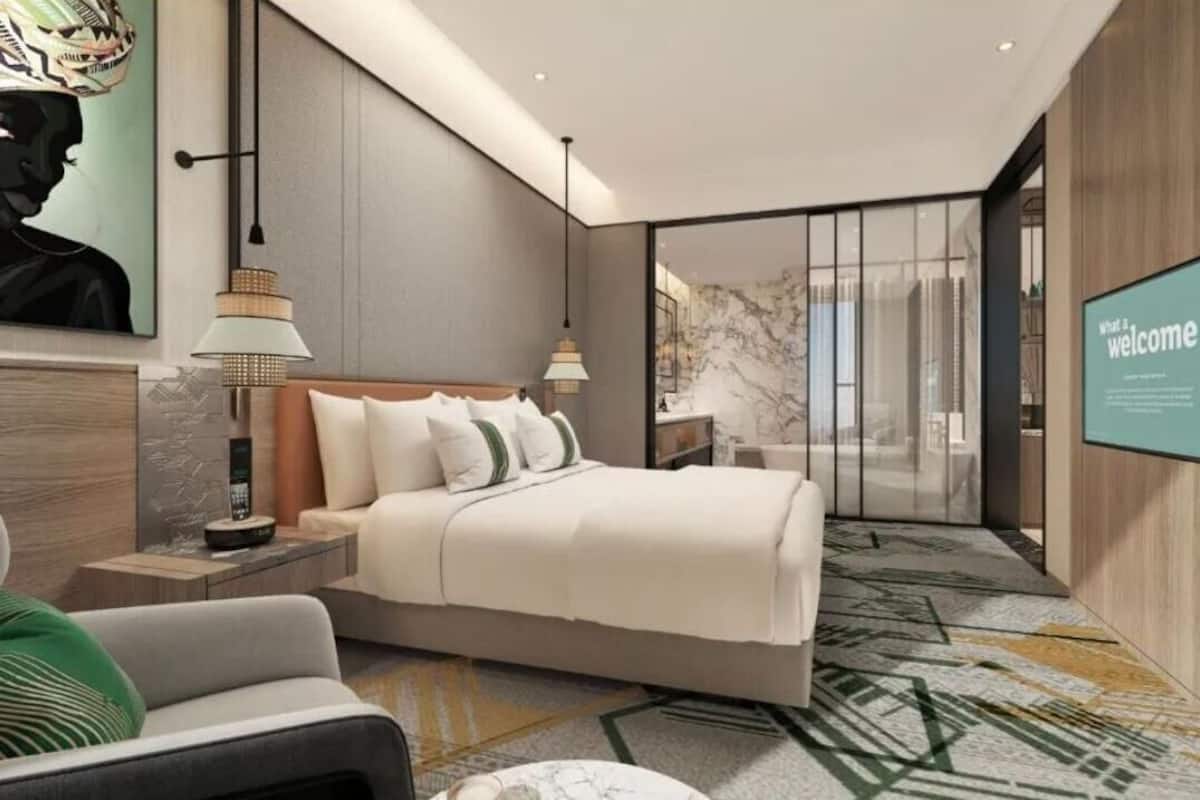 Une chambre d’hôtel moderne avec un grand lit, des tables de chevet, un bureau et une grande fenêtre.