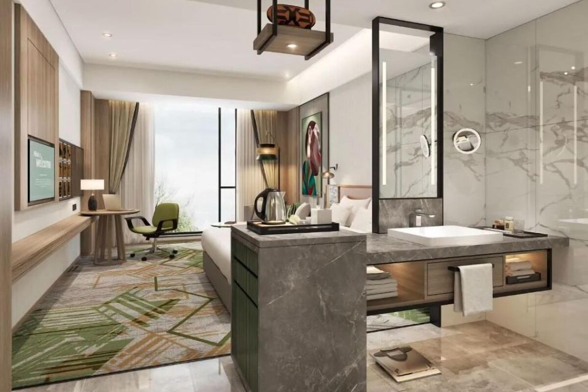 Un baño de hotel moderno con un espejo grande, una bañera y un lavabo.
