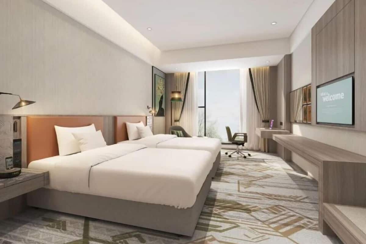 Une chambre d’hôtel moderne équipée d’un grand lit, d’un bureau, d’une chaise et d’un téléviseur.