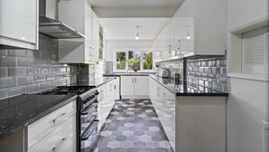 A modern kitchen with white cabinets, a black countertop, and a hexagonal patterned floor. - 3 Bedroom Home Sleeps 7 OR 8 Free Parking NR Solihull Edgbaston and City Centre (Birmingham)