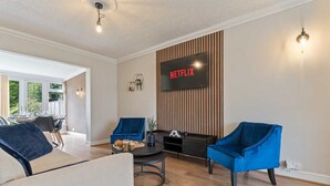 A modern living room with a flat-screen TV displaying 'NETFLIX', two blue armchairs, a round coffee table, and a sofa. - 3 Bedroom Home Sleeps 7 OR 8 Free Parking NR Solihull Edgbaston and City Centre (Birmingham)