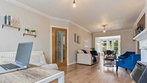 A modern living room with a laptop on a table, a sofa, a blue armchair, and a fireplace. - 3 Bedroom Home Sleeps 7 OR 8 Free Parking NR Solihull Edgbaston and City Centre (Birmingham)