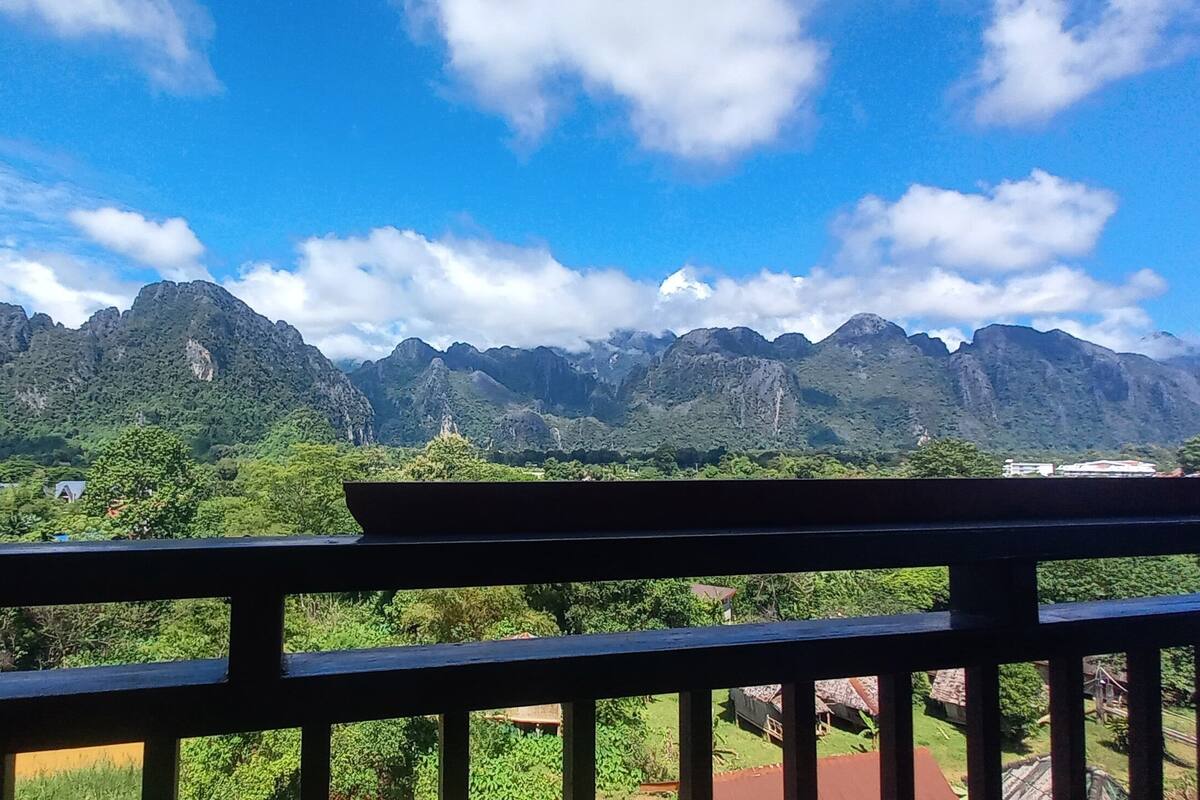 A balcony with a view of mountains and greenery.