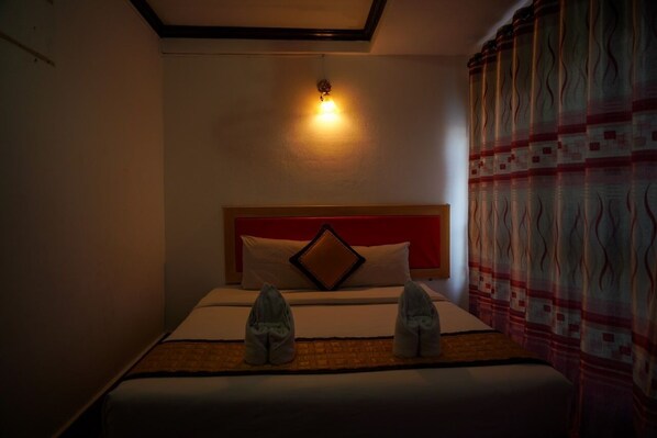 A hotel room with a bed, a headboard, a wall-mounted light, and a patterned curtain. - Bountang Mountain View Riverside Hotel (Vang Vieng)