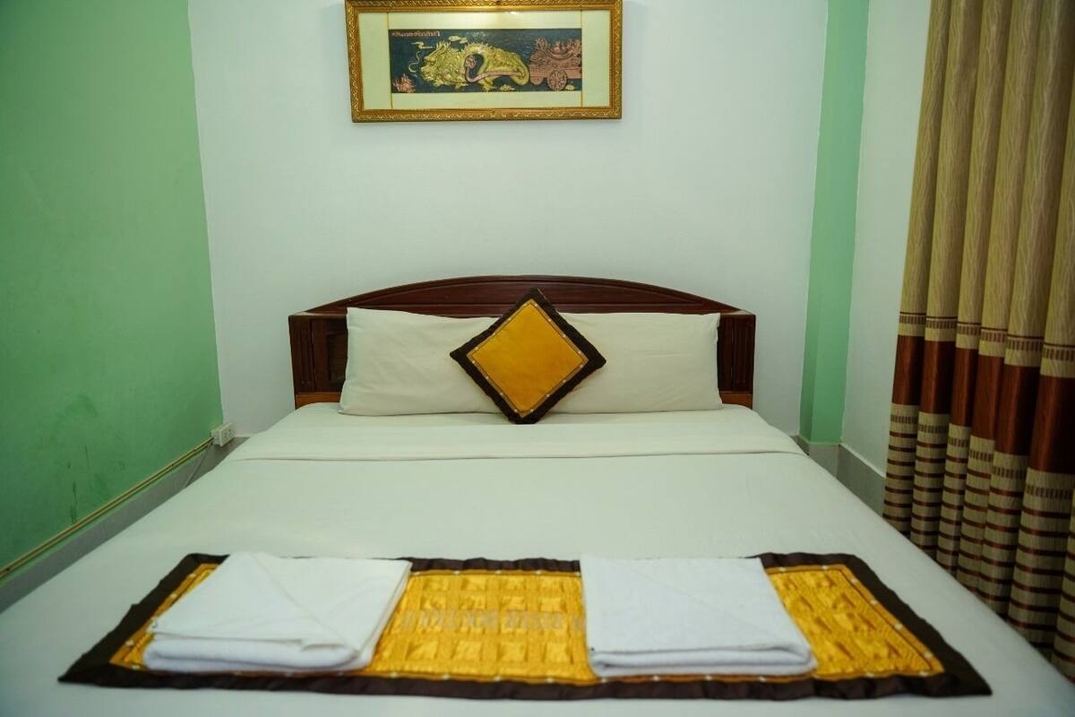 A hotel room with a bed, a framed picture on the wall, and curtains.