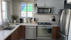 A modern kitchen with stainless steel appliances, wooden cabinets, and a dishwasher. - Vidalia 3 - New Condo with Gym and Rooftop Terrace with Jacuzzi (Puerto Vallarta)