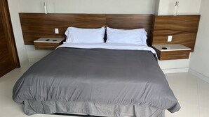 A modern bedroom with a large bed, wooden headboard, two bedside tables, and a nightstand with a remote control. - Vidalia 3 - New Condo with Gym and Rooftop Terrace with Jacuzzi (Puerto Vallarta)