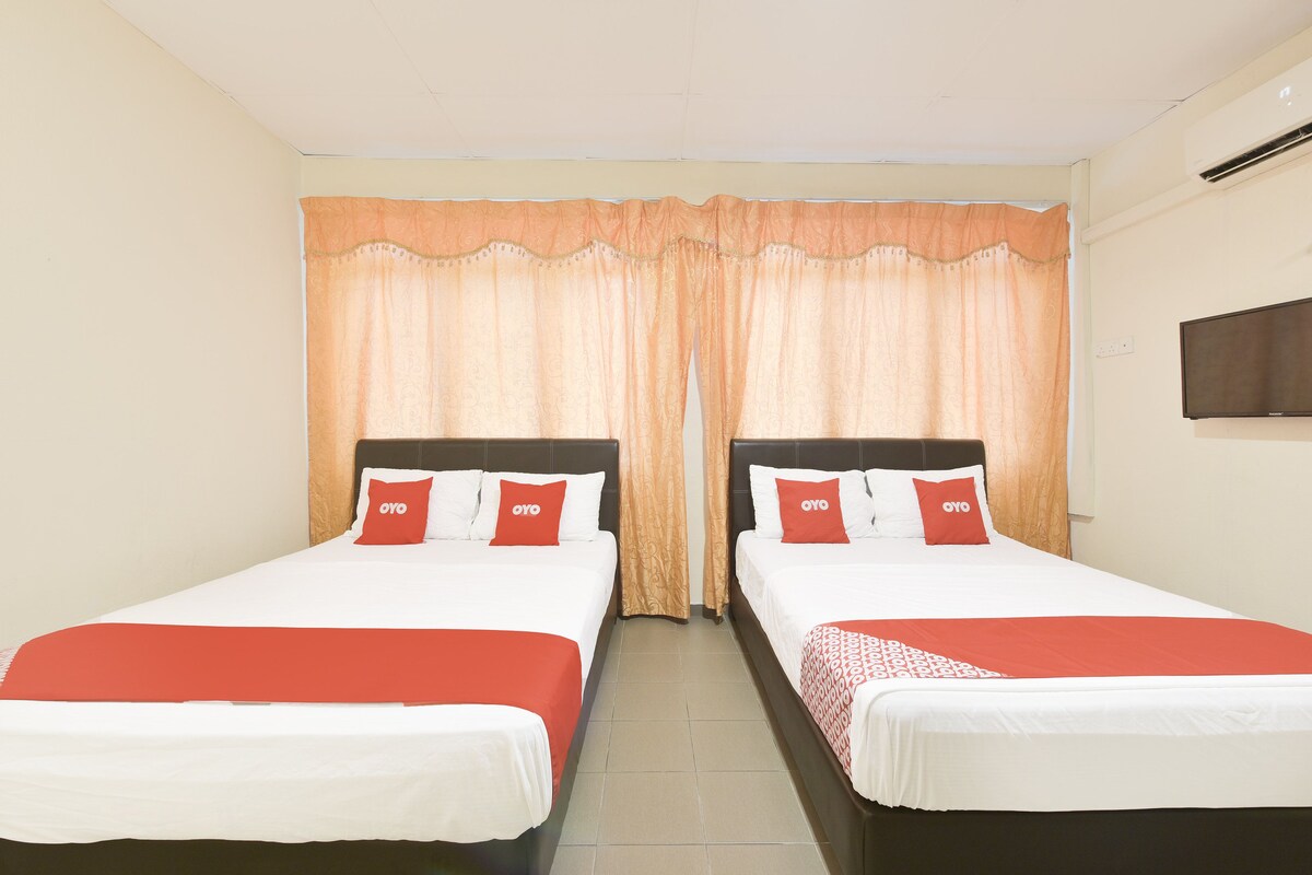 A hotel room with two beds, each with a white and red bedspread, and matching pillows with the logo 'OYO'.