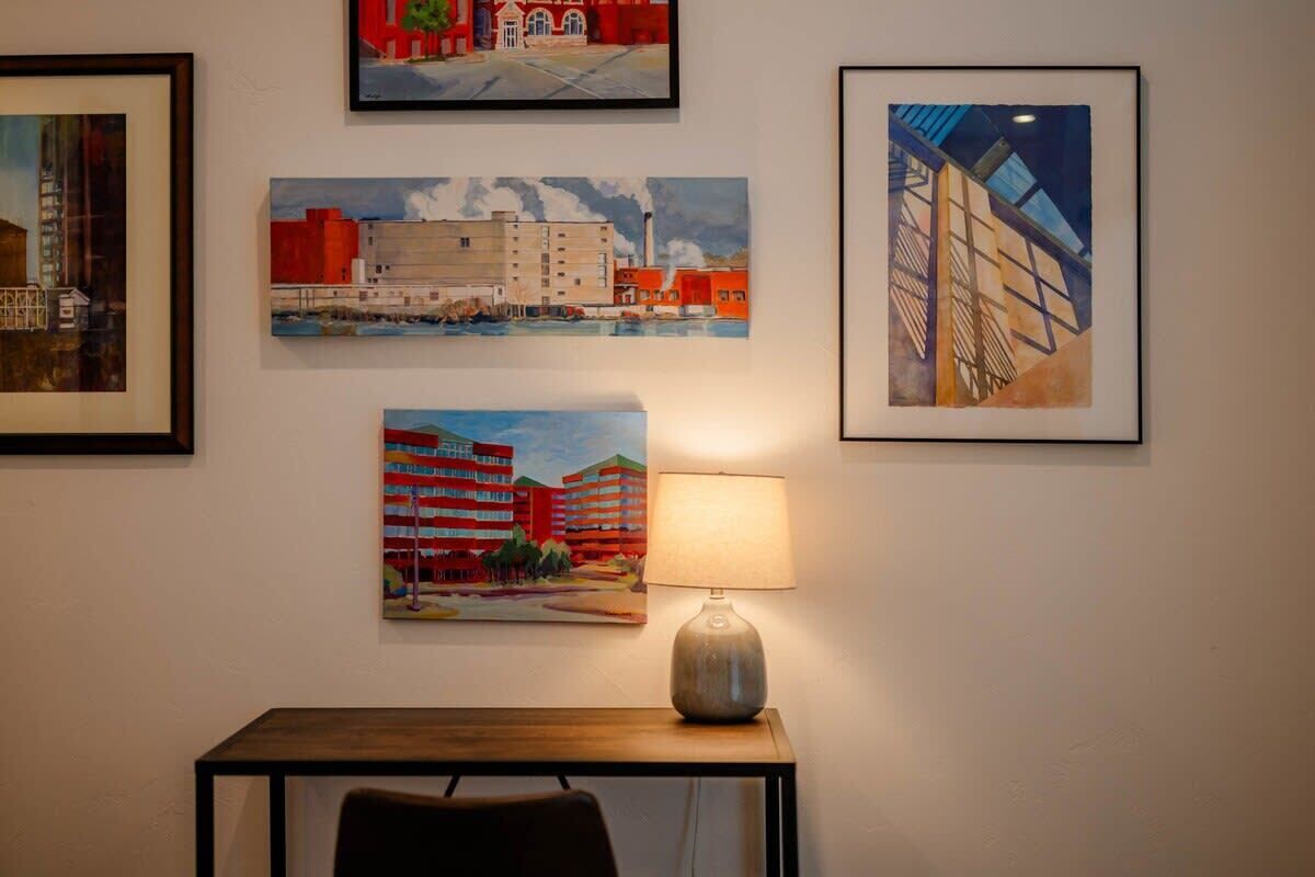 Une pièce comprenant une table, une lampe et quatre tableaux encadrés accrochés au mur.