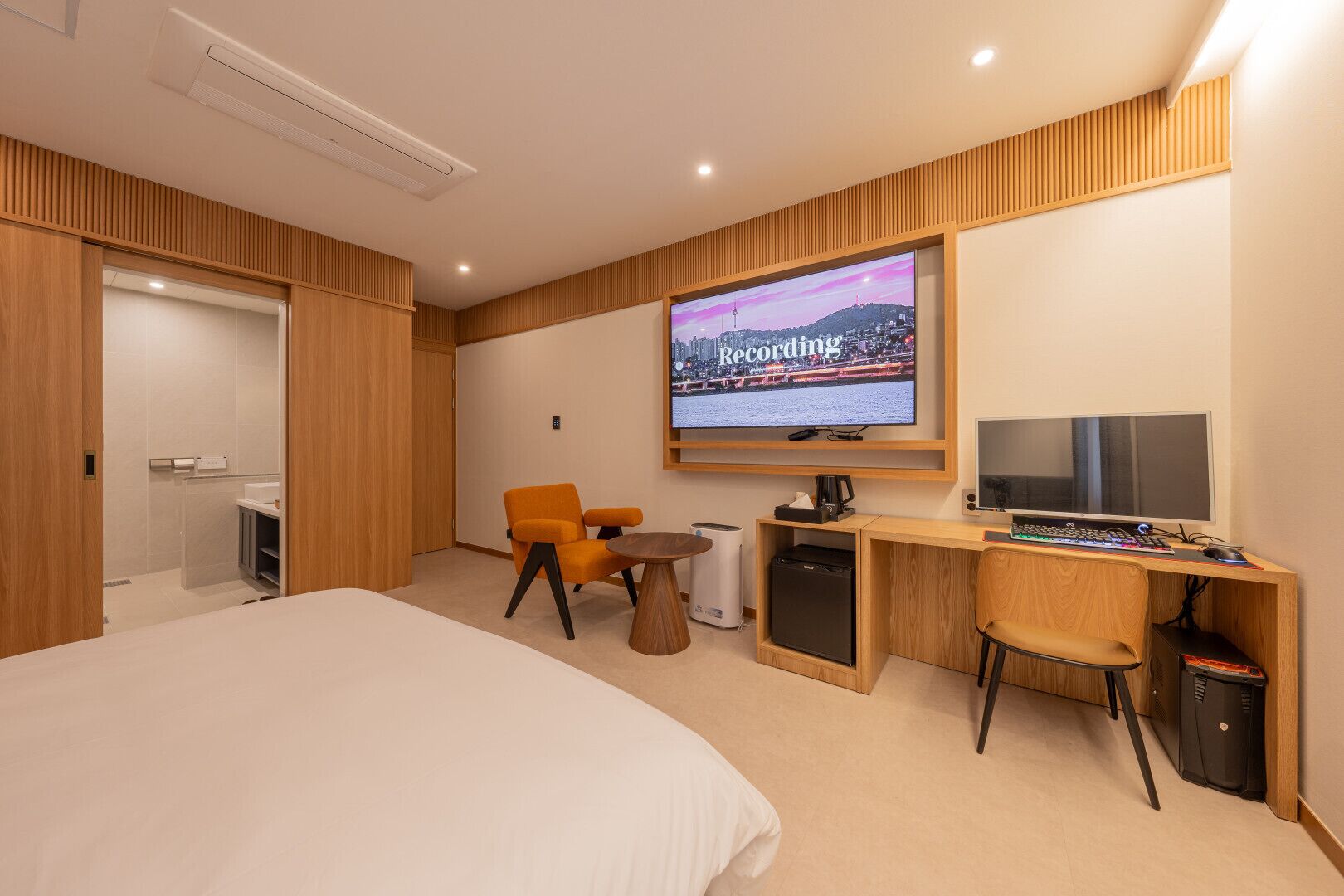 A hotel room with a large bed, a desk with a computer, a TV, and a chair.