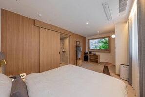 A modern hotel room with a large bed, a TV mounted on the wall, a small table, and a wardrobe. - H Avenue Munhyeon (Busan)