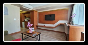 A modern living room with a flat-screen TV mounted on the wall, a wooden coffee table with a vase of flowers, and a dining area with a wooden table and chairs. - Mb Residence Osmanbey (Istanbul)