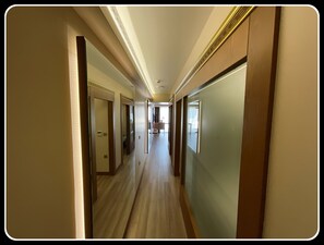 A hotel corridor with wooden floors, doors, and a light-colored wall. - Mb Residence Osmanbey (Istanbul)