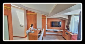 A modern hotel room with a dining area, a flat-screen TV mounted on the wall, and a large window providing a view. - Mb Residence Osmanbey (Istanbul)