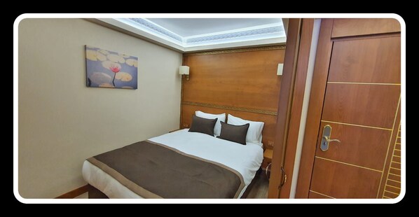 A hotel room with a bed, a painting on the wall, and a wooden door. - Mb Residence Osmanbey (Istanbul)