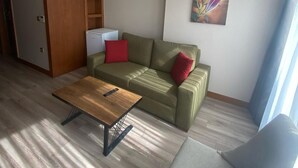 A living room with a sofa, a coffee table, and a chair. There is a painting on the wall and a ceiling light. - Mb Residence Osmanbey (Istanbul)
