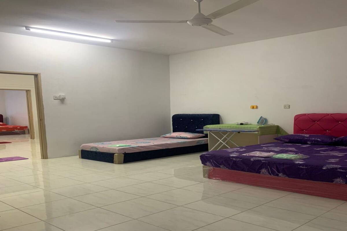 A room with two beds, a ceiling fan, and a small table with a green tablecloth.
