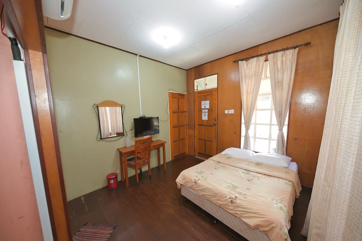 A bedroom with a bed, a desk with a chair, a television, and a wardrobe.