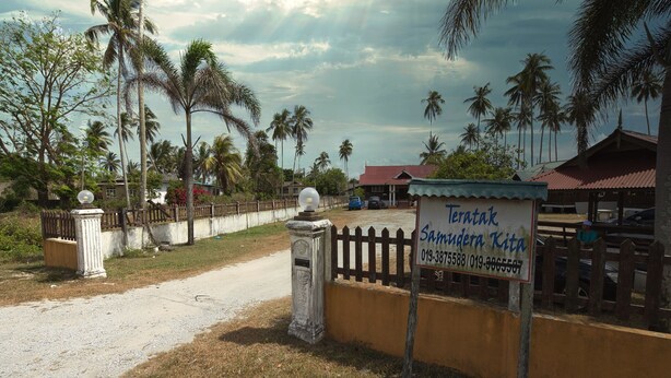 A gated entrance with a sign for Teratak Samudera Kita, a dirt road, and palm trees. - Hotel O Teratak Samuderakita, Chalet & Guesthouse (Kuala Terengganu)