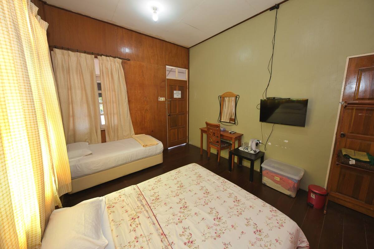 A room with a bed, a desk, a chair, a television, and a wardrobe.