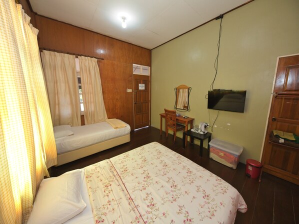A room with a bed, a desk, a chair, a television, and a wardrobe.