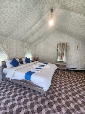 A spacious, well-lit tent-style room with a large bed, patterned carpet, and a window with curtains. - Snowber Resorts (Gund)