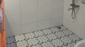 A small, tiled shower room with a handheld showerhead and a wall-mounted faucet. - Riverside Garden Hostel (Vang Vieng)