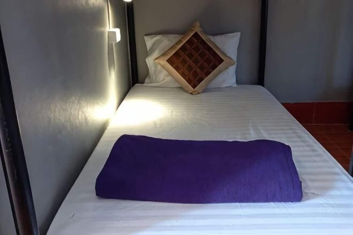 A bed with a white mattress, a purple blanket, and a wooden-patterned pillow.