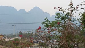 A riverside view with wooden benches, a bridge, and mountains in the background. - Riverside Garden Hostel (Vang Vieng)
